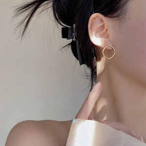 Boucles d'oreilles créoles dorées géométriques irrégulières vue rapprochée sur modèle