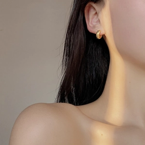 Close-up of golden S925 sterling silver hoop earrings with textured hammered finish