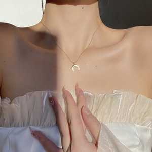 Close-up of minimalist 18K gold crescent moon pendant necklace on a female model