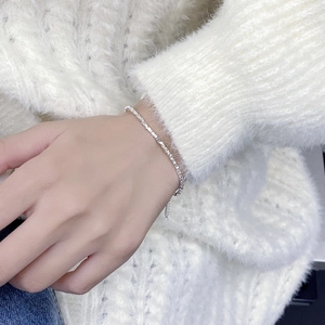 Detailed shot of faceted silver beads on an adjustable bracelet over a plush knit fabric