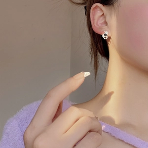 Close-up of irregular silver stud earring with black gemstone on ear with purple sweater