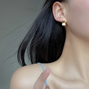 Close-up of minimalist gold geometric rectangular earrings worn by a model