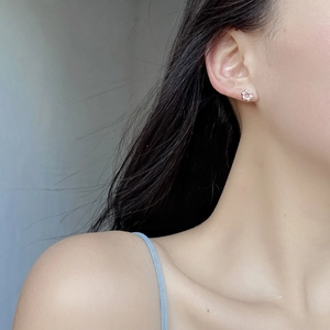 Close-up of minimalist S925 sterling silver flower stud earring worn on earlobe