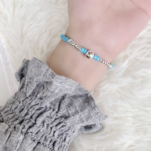 Macro detail of turquoise beaded bracelet with silver accents worn on a wrist