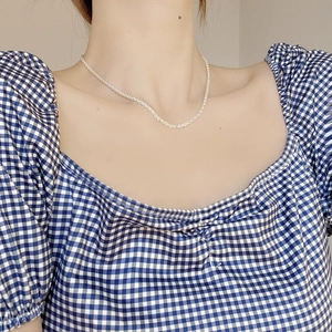 Macro shot of shimmering S925 sterling silver rope chain on model's neckline
