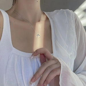 Detailed view of polished silver crescent moon pendant worn on a delicate chain