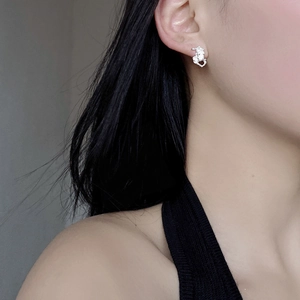 Close-up of irregular sterling silver stud earrings with an artistic crushed metal texture