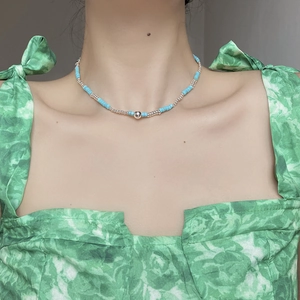 Detail of turquoise cylinder beads and silver sphere pendant necklace worn by a model