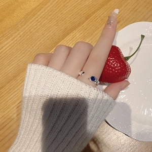 Detail of S925 silver ring with blue zircon and lava texture worn on hand with strawberries