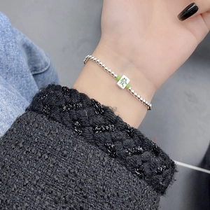 Detail of S925 silver beaded bracelet with green Mahjong tile charm on wrist