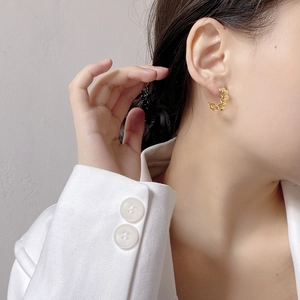Detailed close-up of a gold wave texture C-shape earring worn by a model in white suit