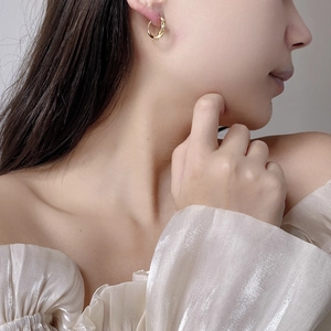 Close-up of elegant gold twisted rope hoop earring worn by a model for size and detail