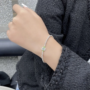 Macro detail of S925 silver beaded bracelet with a green Mahjong Fa charm on wrist