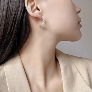 Close-up of wavy S925 silver stud earrings with pearl accents on a female model