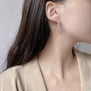 Close-up of S925 sterling silver curved bead earrings following the earlobe contour