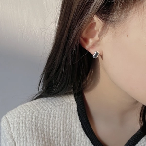 Macro shot of minimalist silver rectangle stud earrings on a model with premium style