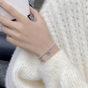 Gros plan d'un bracelet perlé en argent S925 avec pendentif donut bleu clair au poignet