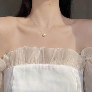 Close-up of elegant freshwater pearl necklace worn with white off-shoulder clothing