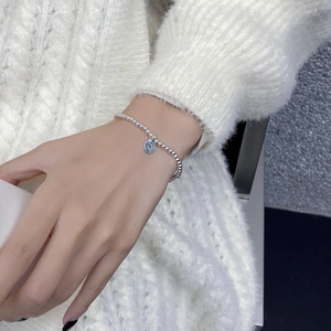 Détail du bracelet en perles d'argent S925 avec breloque donut en émail bleu au poignet
