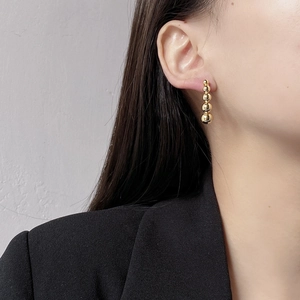 Detailed close-up of gold gradient bead drop earrings featuring five graduated spheres