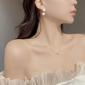 Detailed view of baroque freshwater pearl necklace and double pearl earrings on model