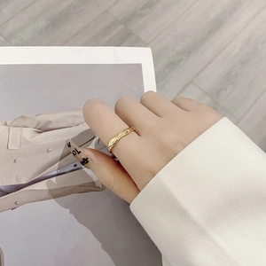 Close-up of a gold minimalist irregular wavy ring on finger with aesthetic magazine background