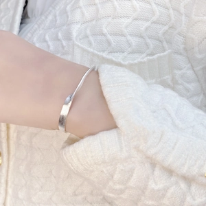 Close-up of matte 925 sterling silver cuff bracelet worn on a white knit sleeve
