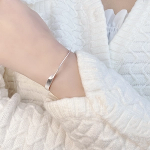 Detail of 925 sterling silver open bangle with a twisted design on a female wrist
