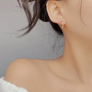 Close-up of elegant gold twisted hoop earring with wave texture worn by a model