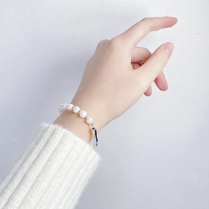 Elegant baroque pearl bracelet on wrist featuring a modern silver branch clasp detail