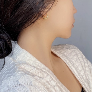 Close-up of elegant triple layered gold hoop earrings worn by a model in a knit sweater