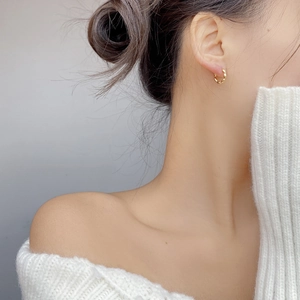 Detailed close-up of a twisted gold hoop earring on a model for a minimalist jewelry look