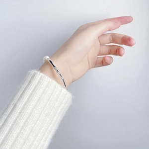 Close-up of S925 sterling silver wavy cuff bracelet with a natural baroque pearl detail