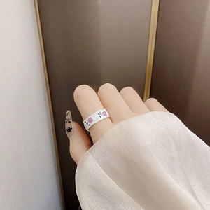 Detail showing white enamel tulip flower relief pattern on minimalist silver ring