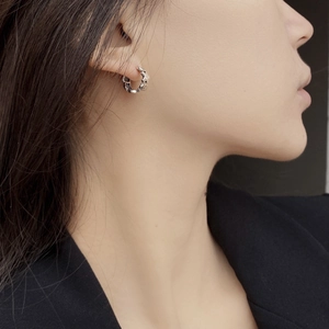 Macro detail of silver graffiti gingerbread man earring worn on model's earlobe