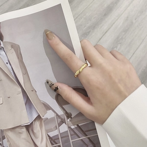 Macro detail of golden wave textured ring worn by a model against a fashion magazine