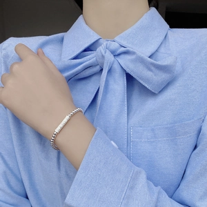 Dettaglio del bracciale con perline in argento S925 e targa Lucky sul polso di una modella