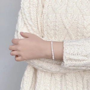 Macro detail of natural freshwater pearl bracelet with S925 silver clasp on knit fabric