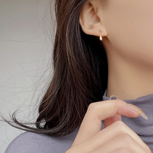 Elegante orecchino a bottone a goccia in argento S925 dorato indossato da una modella