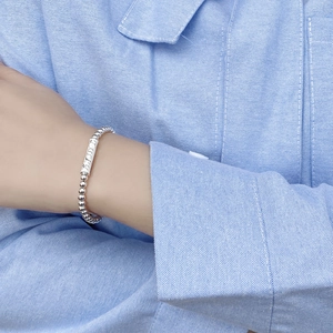 Dettaglio del bracciale di perle in argento S925 con ciondolo Lucky inciso sul polso di modella