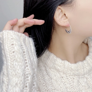 Close-up of S925 sterling silver hoop earrings with embossed texture on a model