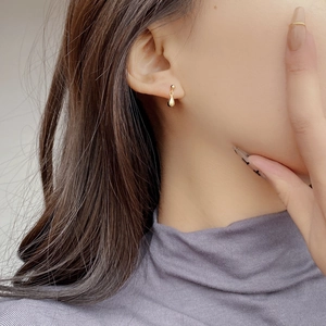 Dettaglio di orecchini a goccia dorati indossati da una modella per uno stile minimalista