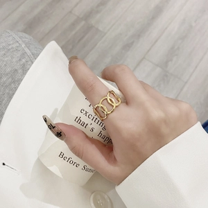 Fashionable golden triple-intertwined ring worn on index finger with a modern white outfit