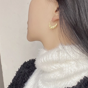 Detail of S925 silver golden textured hoop earring with a hammered molten lava finish