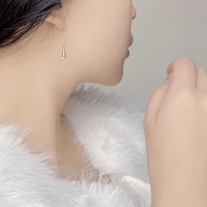 Detailed view of irregular silver teardrop earrings worn by model for elegant style