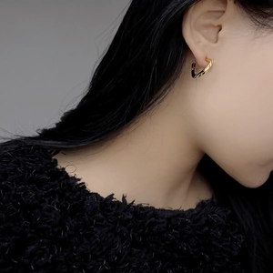 Close-up of a model wearing twisted geometric gold S925 silver hoop earrings