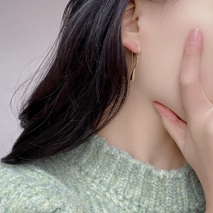 Close-up of elegant gold irregular water drop long earrings on model with green sweater