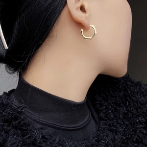 Detail of a minimalist gold geometric hexagonal earring worn by an Asian model