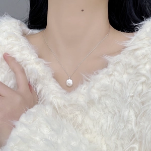 Detail of S925 sterling silver heart pendant necklace on model with white knitwear