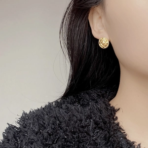 Vintage gold quilted round earrings with beaded edges on model in close-up shot